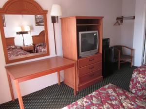 Habitación de hotel con escritorio, TV y espejo. en Westmont Inn - Lakeland en Lakeland