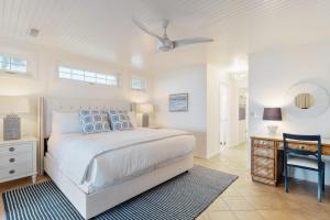 a white bedroom with a bed and a table and a chair at 1001 E Arctic Out of the Blue Stunning Oceanfront Home in Folly Beach