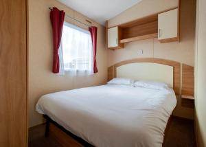 a bedroom with a large bed with a red window at Eastern Beach Caravan Park in Caister-on-Sea