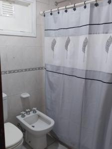 y baño con cortina de ducha, aseo y lavamanos. en Casa en ostende pinamar en Ostende