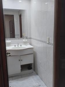 Baño blanco con lavabo y espejo en Casa en ostende pinamar en Ostende