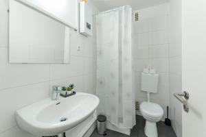 een witte badkamer met een wastafel en een toilet bij T&K Apartments - 3 Room Apartment in Mülheim an der Ruhr