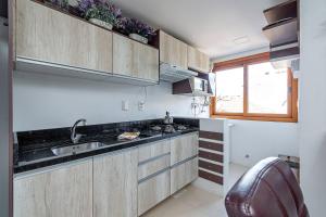 cocina con armarios de madera, fregadero y ventana en Solar da Encosta - Stay House Temporada, en Gramado