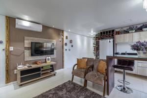sala de estar con sofá, mesa y TV en Solar da Encosta - Stay House Temporada, en Gramado