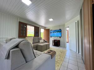 ein Wohnzimmer mit einem Sofa und einem TV in der Unterkunft Casa de Campo no Caruru com açude e piscina in Tubarão