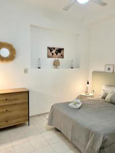 Habitación blanca con cama y tocador de madera. en Terrazas de Rondeau en Mendoza