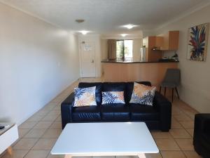 sala de estar con sofá negro y mesa en BEST Ground Floor pool side Superior apartment - new listing en Gold Coast