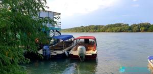 łódź jest zaparkowana w wodzie na jeziorze w obiekcie Hotel Restaurant Plutitor Delta Ways w mieście Nufăru