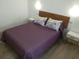 ein kleines Schlafzimmer mit einem lila Bett mit zwei Kissen in der Unterkunft Sunset La Palmita in La Victoria de Acentejo + 30 Fotos