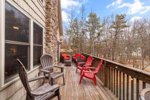 a deck with red chairs and tables and windows at THE ONE Chalet in Albrightsville