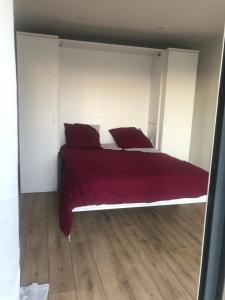 a bed with red sheets and pillows in a bedroom at La Perle Rare - spa in La Selle-en-Coglès