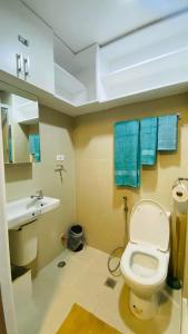 a bathroom with a toilet and a sink with blue towels at Cozy 1Br with Netflix & Balcony Pool View Condo in Manila