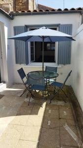 a table and chairs under an umbrella on a patio at Logement idéal curistes in Rochefort