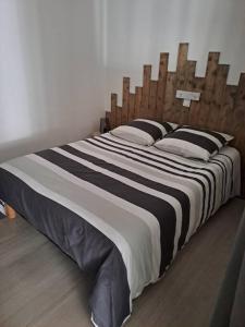 duże łóżko z drewnianym zagłówkiem w sypialni w obiekcie Logement idéal curistes w mieście Rochefort