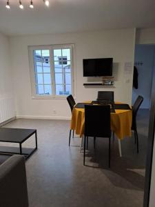 Habitación con mesa con sillas y TV. en Logement idéal curistes en Rochefort