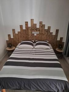 ein großes Bett mit einem Kopfteil aus Holz im Schlafzimmer in der Unterkunft Logement idéal curistes in Rochefort