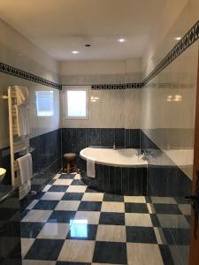 a bathroom with a tub and a checkered floor at The garden house & aloès bien-être spa in Vierzon