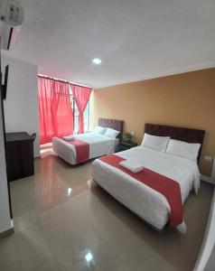 zwei Betten in einem Hotelzimmer mit roten Vorhängen in der Unterkunft HOTEL DIAMANTE in Santo Domingo de los Colorados