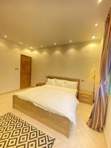 a bedroom with a large bed and a rug at فيلا آفيري Aviary villa in AlUla