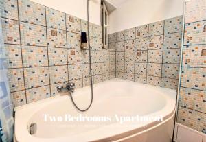 a bath tub in a bathroom with tiled walls at Comfy&Bright 2BD Family-Friendly APT Amazing View in Bucharest