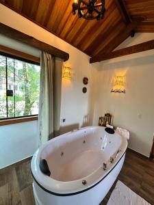 a large white bath tub in a room with a window at Flor de Minas in Monte Verde