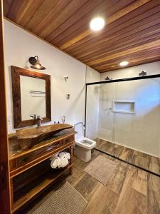 een badkamer met een wastafel, een toilet en een spiegel bij Flor de Minas in Monte Verde