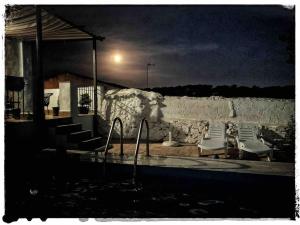 - une piscine avec des chaises longues à côté d'un mur en pierre dans l'établissement CASA RURAL LOS ALTOS, à Ojuelos Altos