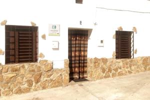 a building with two windows and a stone wall at CASA RURAL LOS ALTOS in Ojuelos Altos