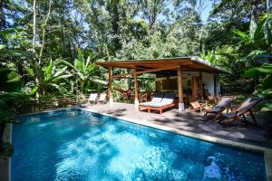 a swimming pool with a gazebo and a house at Satta Lodge in Puerto Viejo