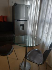 una mesa de cristal y sillas en la sala de estar con nevera. en Hermoso Apartamento en el centro de Buenos Aires. en Buenos Aires