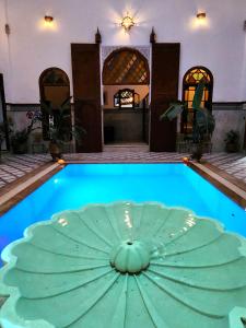 Le Riad Palais d'hotes Suites & Spa Fes في فاس: مسبح في المنتصف فيه مظلة خضراء