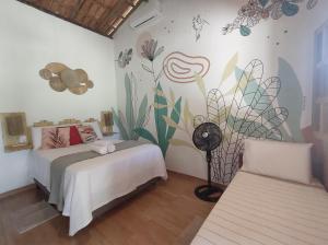 een slaapkamer met 2 bedden en een muurschildering aan de muur bij Pousada Quintal dos Sonhos Xandó Caraiva in Caraíva