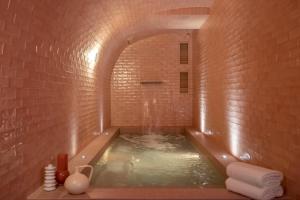uma casa de banho com uma banheira numa parede de tijolos em Le Petit Oberkampf Hotel & Spa em Paris