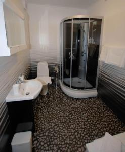 a bathroom with a shower and a toilet and a sink at Avesta Stadshotell in Avesta