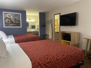 a hotel room with two beds and a flat screen tv at Days Inn by Wyndham Portland/Corpus Christi in Portland