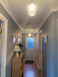 a hallway with a door and a table with a lamp at Brada View Bamburgh in Bamburgh