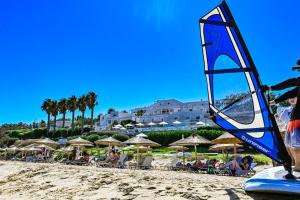 a beach with umbrellas and people sitting on the sand at Saint George Hotel in Chrissi Akti
