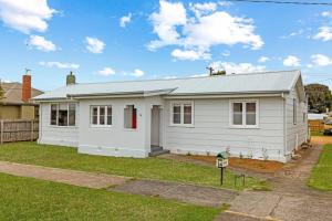 a white house with a red door in a yard at Coastal Cottage Warrnambool in Warrnambool +12 photos