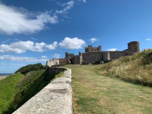 a castle on a hill next to the ocean at Brada View Bamburgh in Bamburgh