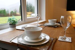 a wooden table with plates and wine glasses on it at Achintee Cottages No 1 in Fort William