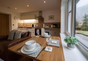 a kitchen and living room with a wooden table with glasses at Achintee Cottages No 1 in Fort William