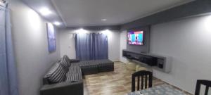 sala de estar con sofá y TV de pantalla plana en Chalet Privado en Complejo "Los Teros" en San Rafael