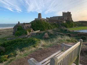 a bench on a hill with a castle in the background at Brada View Bamburgh in Bamburgh
