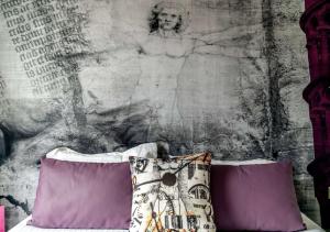 una cama con almohadas moradas y una pared con una pintura en Best Western Le Vinci Loire Valley, en Amboise