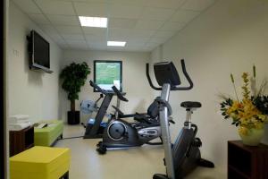 einen Fitnessraum mit zwei Heimtrainern in einem Zimmer in der Unterkunft Hôtel Le Palladior Voiron in Voiron