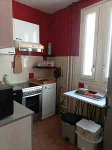 cocina con paredes rojas, fogones y ventana en La Boussole - Maison meublée 3 chambres 6 pers., en Chinon