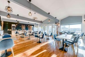 un restaurant avec des chaises bleues, des tables et des fenêtres dans l'établissement Sure Hotel by Best Western Bordeaux Lac, à Bordeaux