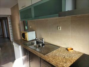 a kitchen counter with a sink and a microwave at The Ferry House in São Jacinto