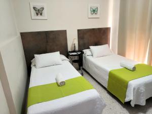 two beds with green and white sheets in a room at Pension Perez Montilla in Seville