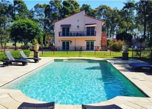 a house with a swimming pool in front of a house at Villa Provence Estate in Pokolbin